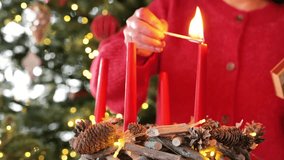 First Advent. Christmas wreath with four red candles.First week of Christmas. Woman lights first candle of Advent wreath on Christmas beautiful tree background.Christmas traditions and customs - Powered by Shutterstock - Get 15% off with code: PIKWIZARD15