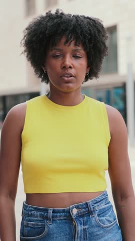 Vertical individual portrait of one serious teenage african american girl looking at camera outside. A pensive young adult woman staring front . Proud afro female gazing with thoughtfull expression