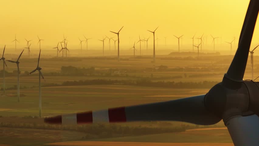 Close-up of windmill blade spinning against golden sunset. Renewable energy and its impact on the environment. Wind farm - aerial view. (4K).