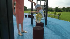 A mother and her little son having fun on the playground. A beautiful woman playing with her toddler in a city park. Traditional active seasonal entertainment for families with children - Powered by Shutterstock - Get 15% off with code: PIKWIZARD15