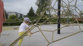 A mother and her little son having fun on the playground. A beautiful woman playing with her toddler in a city park. Traditional active seasonal entertainment for families with children - Powered by Shutterstock - Get 15% off with code: PIKWIZARD15