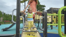A mother and her little son having fun on the playground. A beautiful woman playing with her toddler in a city park. Traditional active seasonal entertainment for families with children - Powered by Shutterstock - Get 15% off with code: PIKWIZARD15