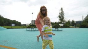 A mother and her little son having fun on the playground. A beautiful woman playing with her toddler in a city park. Traditional active seasonal entertainment for families with children - Powered by Shutterstock - Get 15% off with code: PIKWIZARD15