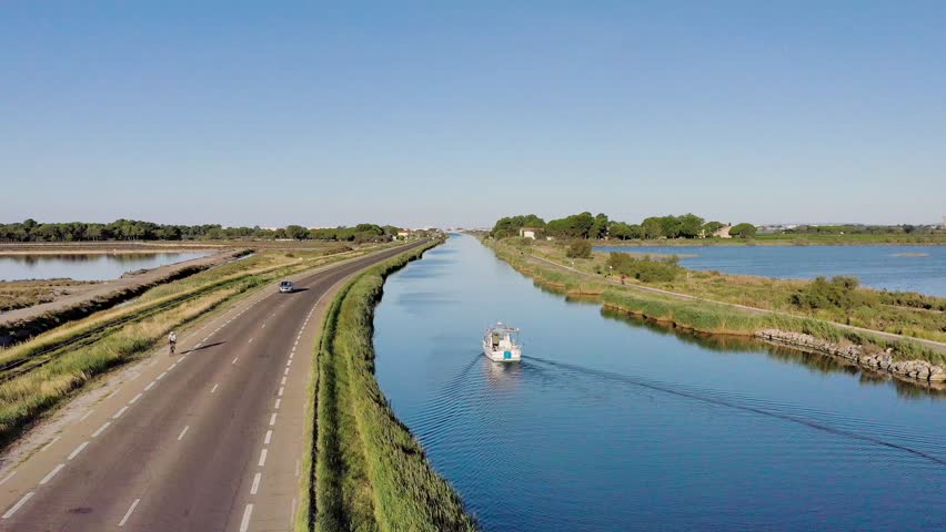 Aerial view of tranquil river with boats and scenic countryside, Aigues Mortes, France.