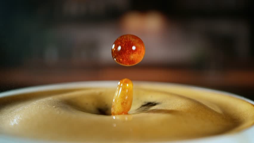 Super Slow Motion Detail Shot of Coffe Drop Falling into Fresh Espresso at 1000 fps . Filmed on High Speed Cinematic Camera at 1000 FPS .