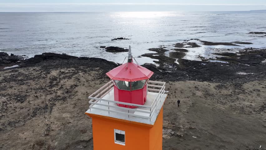 Aerial view of selvogsviti lighthouse on a rocky shore with waves crashing, reykjavik, iceland.