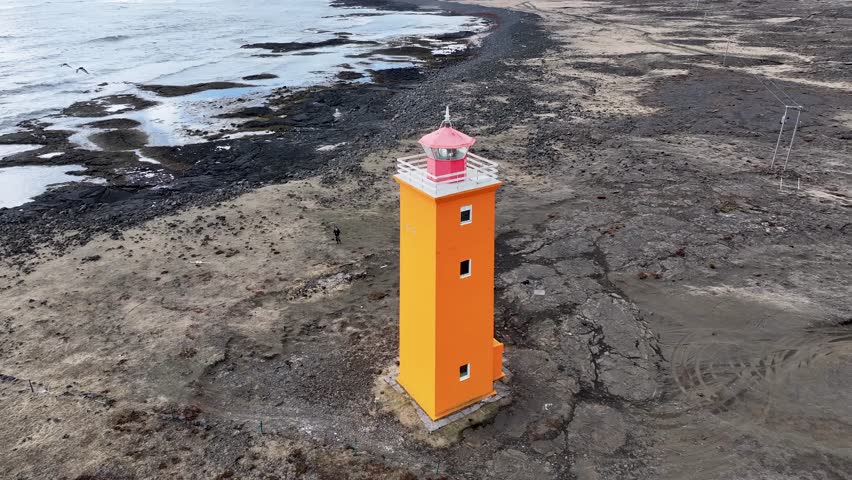Aerial view of selvogsviti lighthouse on a rugged coast with beautiful ocean waves, Reykjavik, Iceland.