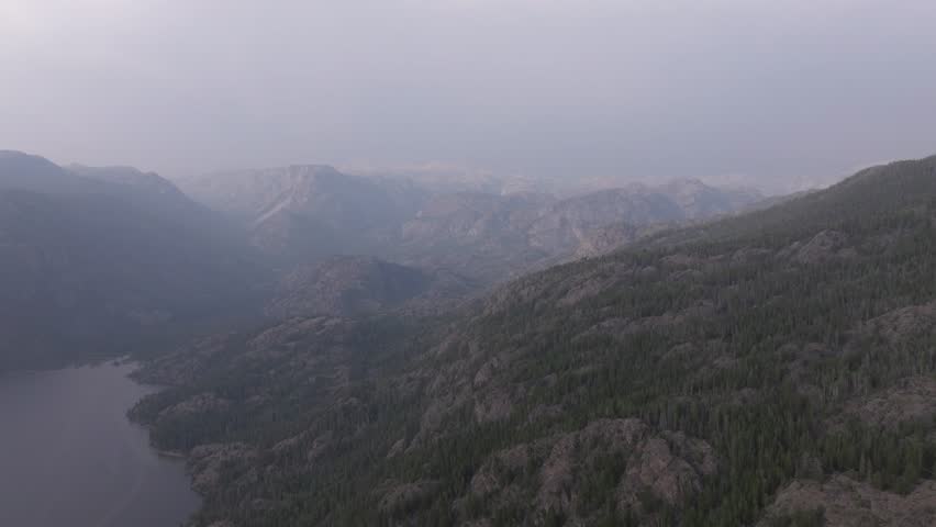 Wind River Range aerial view showcases rugged mountains and a forested valley at dawn