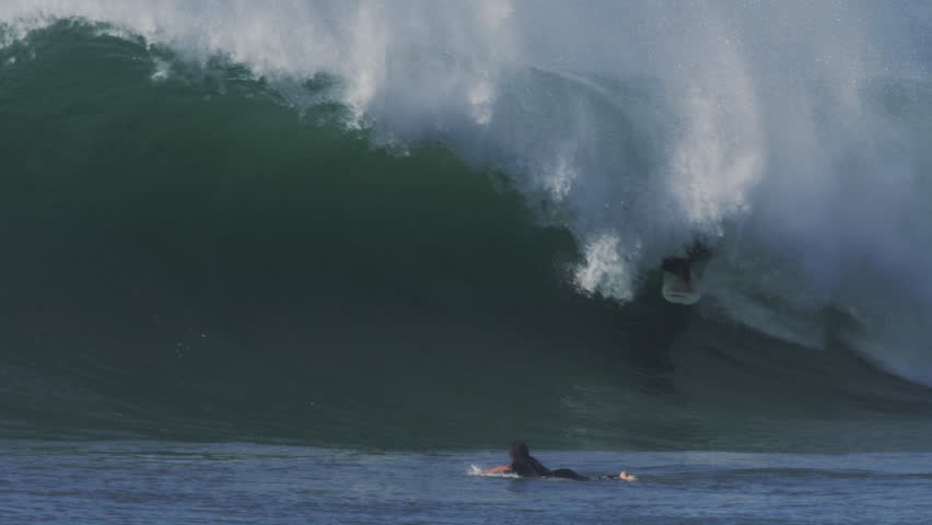 Powerful wave crashing during golden hour, with sunlight illuminating the crest and white water in slow motion.