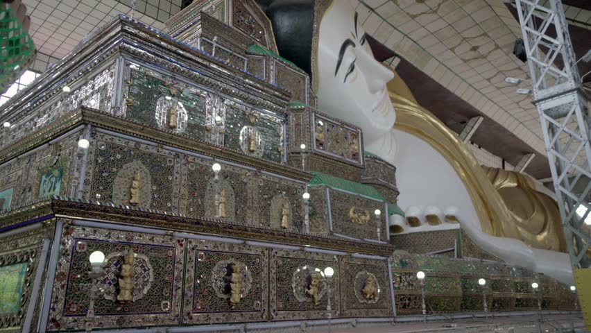 A large statue of Buddha is surrounded by flowers. The statue is white and gold, and the flowers are red. Concept of peace and serenity
