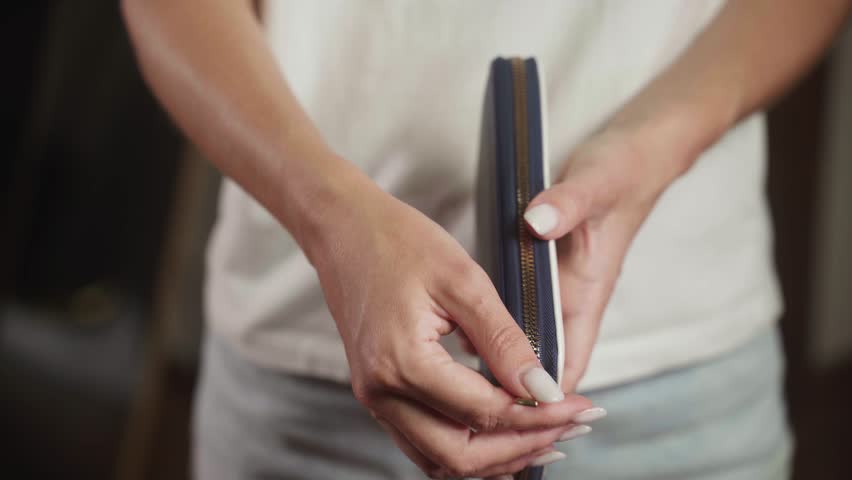 Woman opens an empty wallet, revealing only one coin inside. The scene captures the feelings of financial struggle and the challenges of managing money in tough times