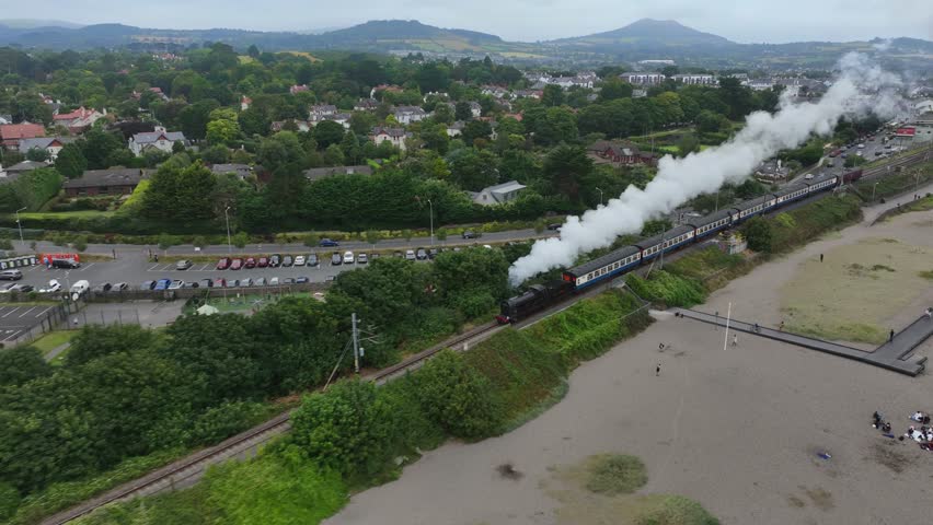 Steam Train, Greystones, County Wicklow, Ireland, September 2024. Drone follows the Dublin Riviera Express pulled by No.131 Steam Locomotive steaming south towards Wicklow town along South Beach.