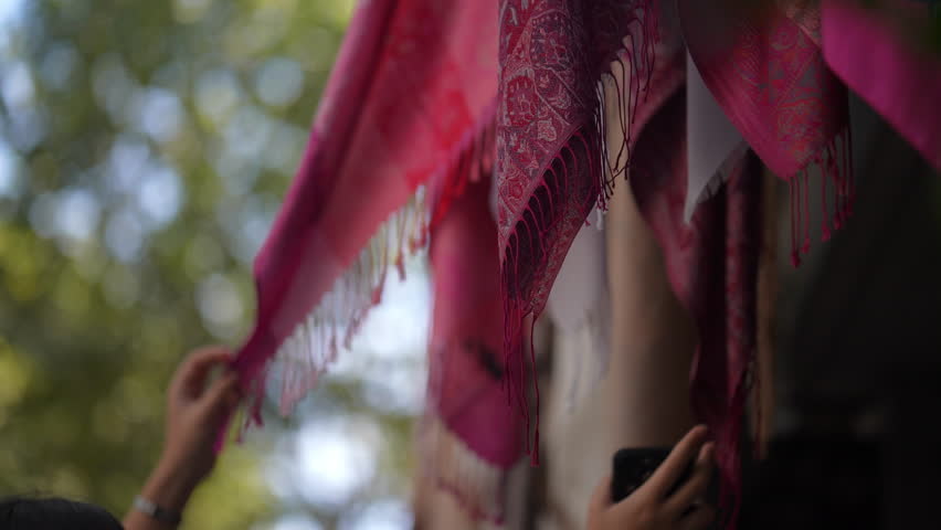 Woman Choosing Scarf Displayed on the Street in Istanbul, Turkey. Concept of Tourism, Shopping, local culture, souvenirs, street market, travel, buying, retail, vacation, Turkish Bazaar, accessories