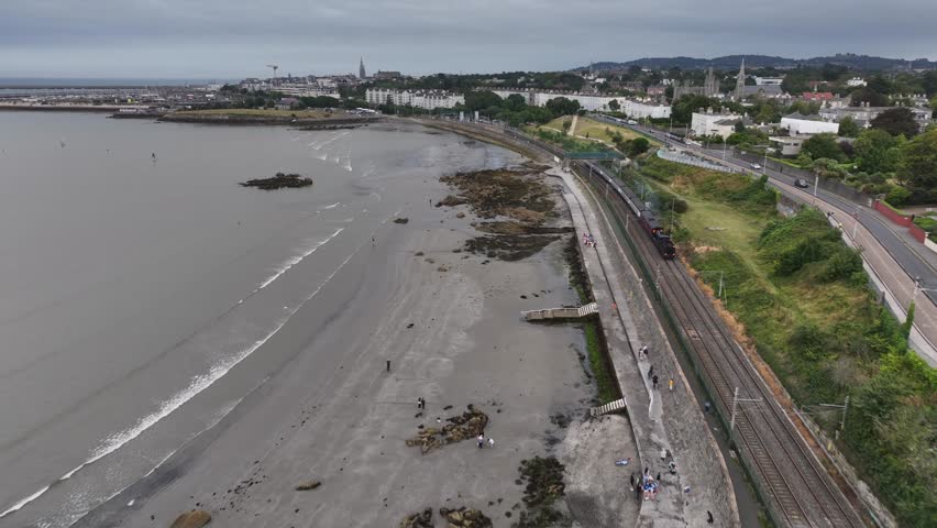 Steam Train, Seapoint, County Dublin, Ireland, September 2024. Drone follows the Dublin Riviera Express pulled by No.131 Steam Locomotive passing the Martello Tower steaming north towards Blackrock.