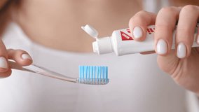 A person applies toothpaste onto a toothbrush while preparing to brush their teeth, showcasing good oral hygiene practices in a well-lit environment. - Powered by Shutterstock - Get 15% off with code: PIKWIZARD15