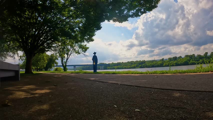footage of a gorgeous summer landscape in the park along a footpath near the rippling waters of the Tennessee River surrounded by lush green trees, grass and plants with blue sky and clouds