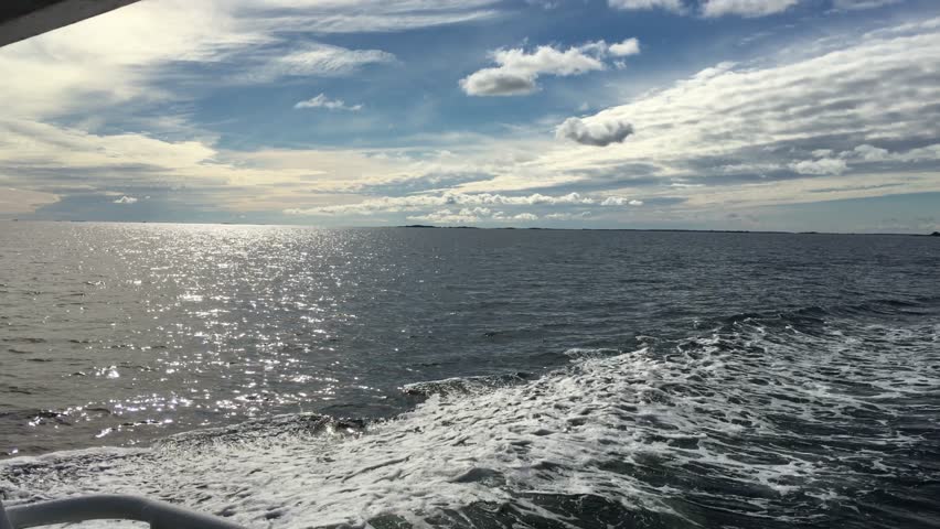 Boat ride through the scenic Roslagen archipelago, far outside Stockholm. The video captures the beauty of a sunny day with clouds scattered across the sky, while the sun glistens on the water