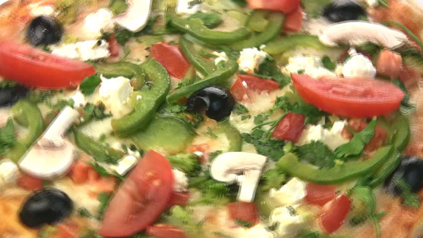 Vegetarian pizza close-up turns, showing all of its stuffing: peppers, olives,