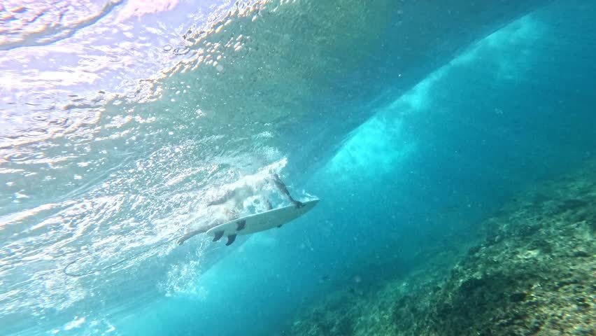 Underwater view of surfer dive under wave breaking over coral reef. Oahu north shore famous action sports destination. travel in Hawaii. slow motion 4k.