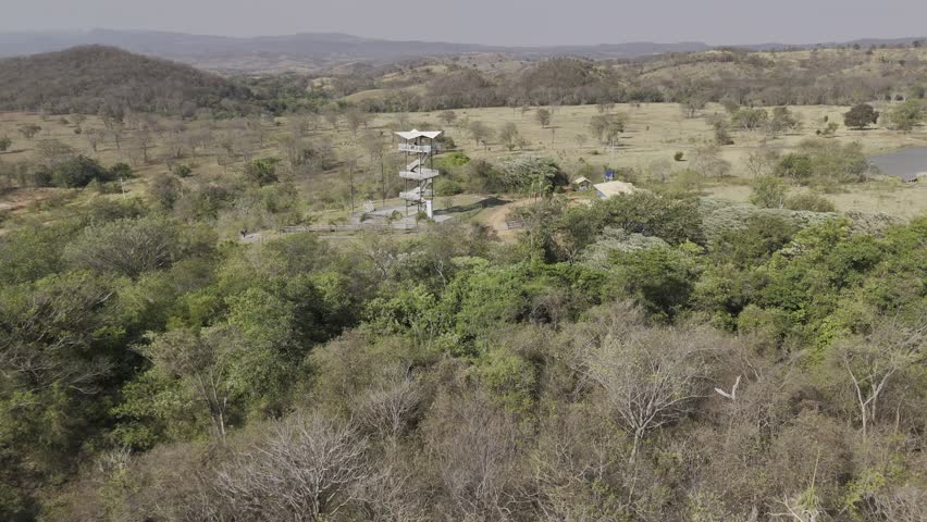 Drone flies toward zip line tower on sunny afternoon