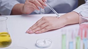 Cosmetic research scene in clinical laboratory, scientist using glass rod to apply moisturizers cream on the back of hand. High angle close up view, laboratory table contains lab glassware - Powered by Shutterstock - Get 15% off with code: PIKWIZARD15
