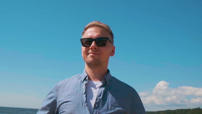 A man wears a shirt on the beach in summer.