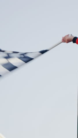 Racing marshal waving Checkered race at finish line on a raceway. Victory, achievement, success and sport concept. Grand Prix. Slow Motion. Vertical frame.