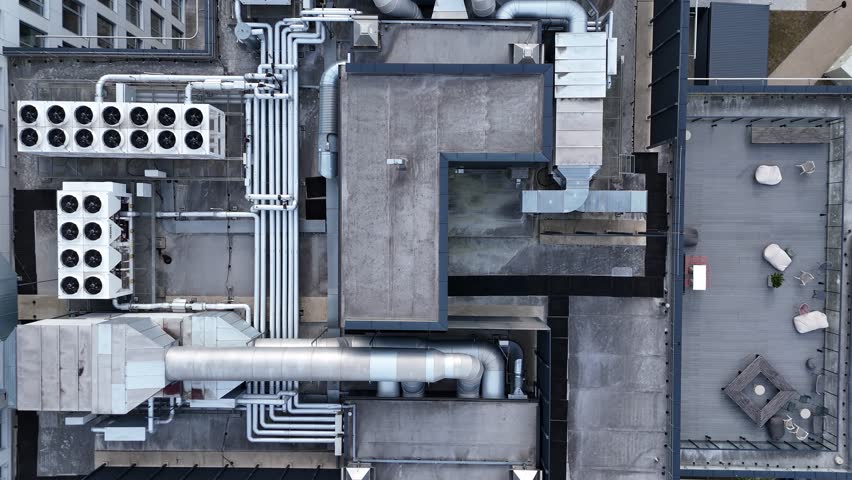 Aerial view of industrial rooftop HVAC and ventilation system. High-angle drone view of rooftop HVAC units, pipes, and ventilation system on an industrial building.