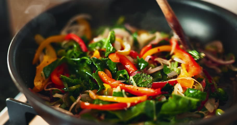 Closeup, spoon and cooking vegetables in house, eating and health with nutrition, flavor and stir fry. Frying, pan and person in kitchen for healthy breakfast, meal prep or food with diet in morning