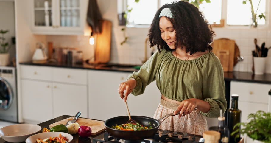 Cooking, taste and woman in kitchen for lunch, food and happy chef at counter with fresh recipe. Diet, wellness and girl at stove for meal prep with smile, nutrition and eating vegetables from pan