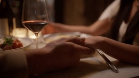 A close-up of a mans affectionate touch as he gently holds his partners hand during a dinner date, highlighting the intimacy and warmth of their connection - Powered by Shutterstock - Get 15% off with code: PIKWIZARD15
