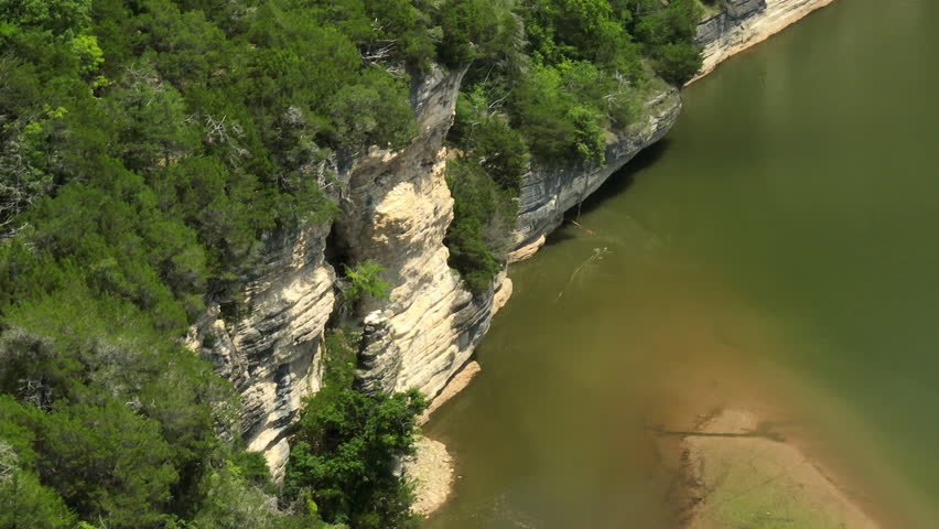 Beaver lake with rocky cliffs and lush greenery on a sunny day, aerial view