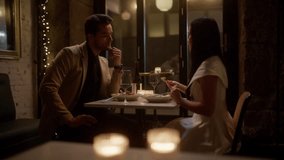 A couple feeds each other their respective meals during a restaurant date, nodding approvingly and smiling with delight at the delicious flavors - Powered by Shutterstock - Get 15% off with code: PIKWIZARD15