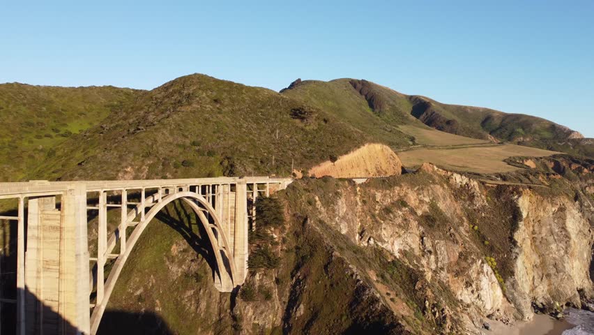 Pacific coast aerial drone view, bridge over a beach during a sunset - 4k