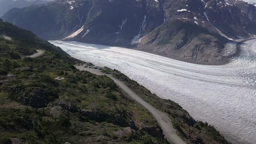 Flyover: Vehicles at viewpoint high above Salmon Glacier in Canada