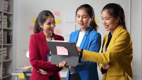 Three young businesswomen are standing in the office and using a digital tablet, discussing and smiling - Powered by Shutterstock - Get 15% off with code: PIKWIZARD15