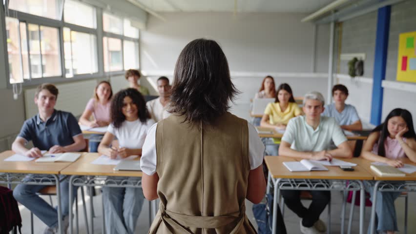College students listen to a passionate, mature female teacher giving a motivational speech during a high school lecture
