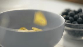 Slow motion footage shows yellow corn kernels falling. A healthy lifestyle enthusiast fills a bowl with breakfast cereal. The nutritious morning meal includes milk and cornflakes - Powered by Shutterstock - Get 15% off with code: PIKWIZARD15
