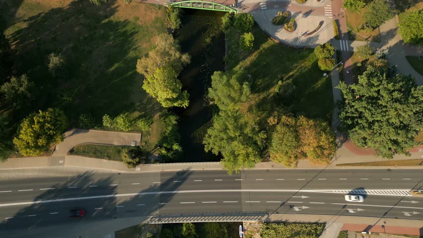 Drone shot reveals urban city park across beautiful river, Elk city gothic architecture buildings and landscape