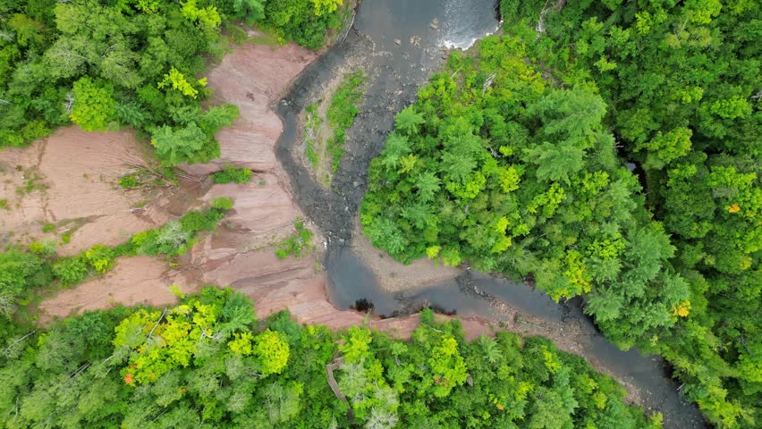 Potato River Falls, Wisconsin: Spectacular Birds Eye Tracking Shot Following The River Bed Upstream. Lush Green Canopies Of Trees Surrounding Both Sides.