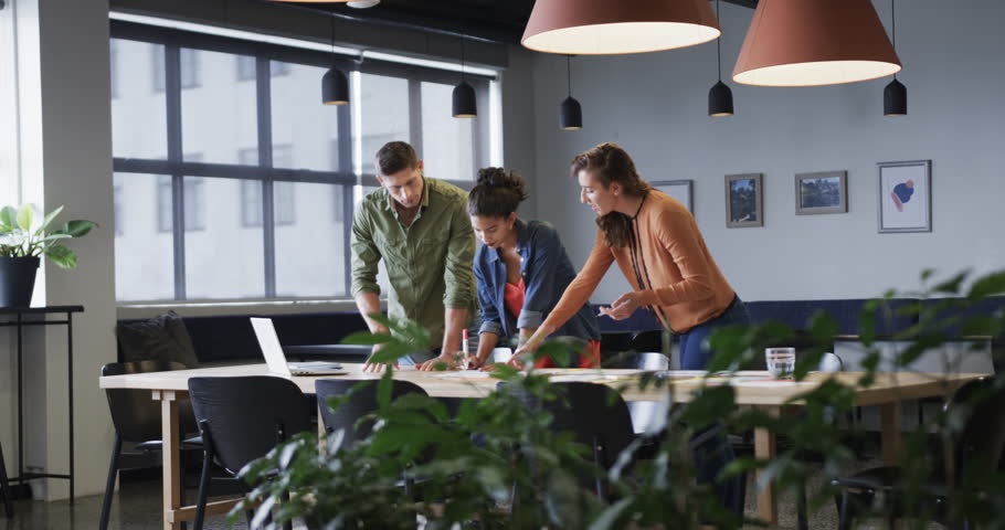 Diverse male and female colleagues in discussion using laptop in casual office meeting. Casual office, teamwork, business, lifestyle and work, unaltered.