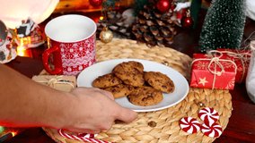 Male hand placing plate with Christmas cookies on a table decorated with Christmas decorations in the background, Christmas food concept - Powered by Shutterstock - Get 15% off with code: PIKWIZARD15