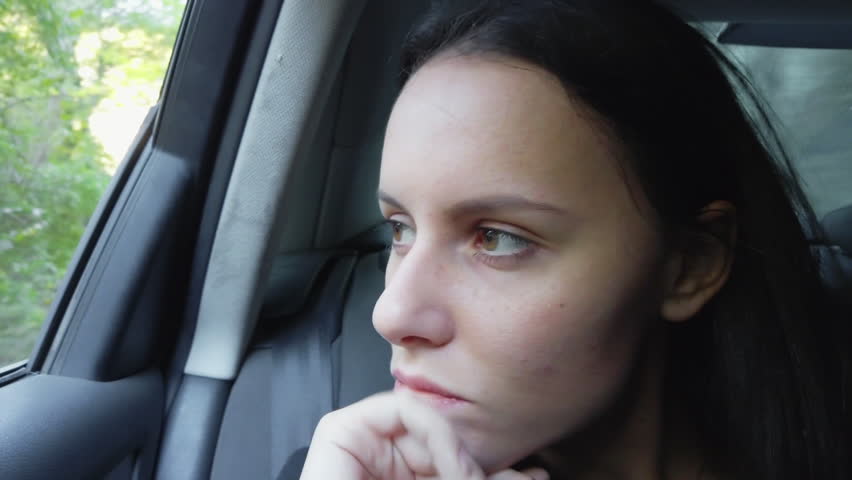 Nervious business young woman in the backseat of a car looking out the window and being anxious