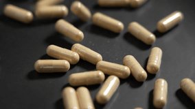 Beige medicine capsules spilling on a black surface in slow motion close up. Medical natural pharmacy and organic health care concept - Powered by Shutterstock - Get 15% off with code: PIKWIZARD15