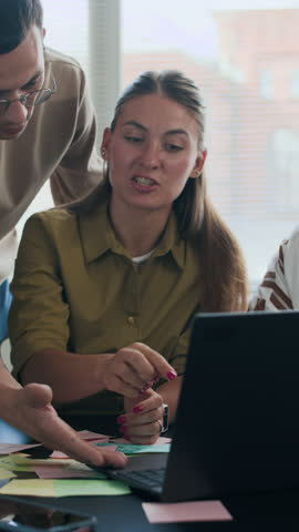 Vertical shot of diverse university students collaborating in group while working on linguistic project together in classroom