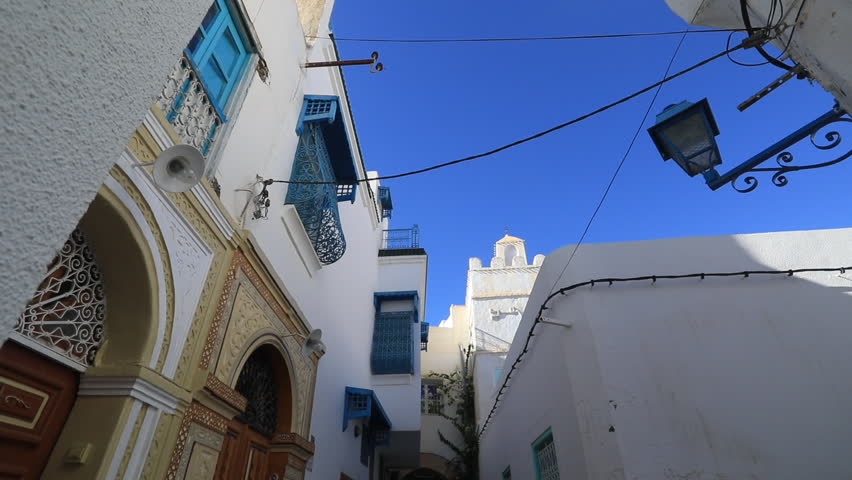 Narrow street in Tunisia lined with traditional buildings and colorful doors under clear sky