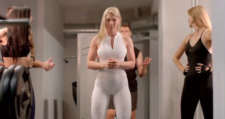 In a vibrant gym, three sport models showcase stylish athletic wear, highlighting strength and style, They are waiting for the start of training with the coach.