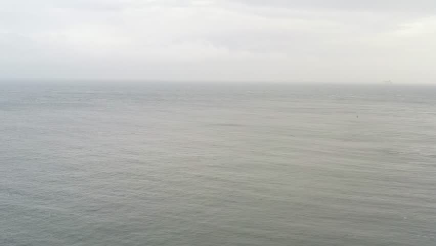 Aerial pullback over misty open waters to Martello Tower overlooking ocean in Howth North Dublin Ireland