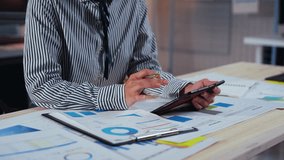 Businesswoman is reviewing financial reports and data analysis on a tablet, comparing with paper charts and graphs at her desk in the office - Powered by Shutterstock - Get 15% off with code: PIKWIZARD15