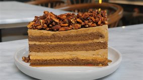 Delicious caramel and nut layered cake slice on white plate in cozy cafe setting, close-up, perfect for gourmet dessert lovers and food photography. Indulgence and Sweet Treats. - Powered by Shutterstock - Get 15% off with code: PIKWIZARD15